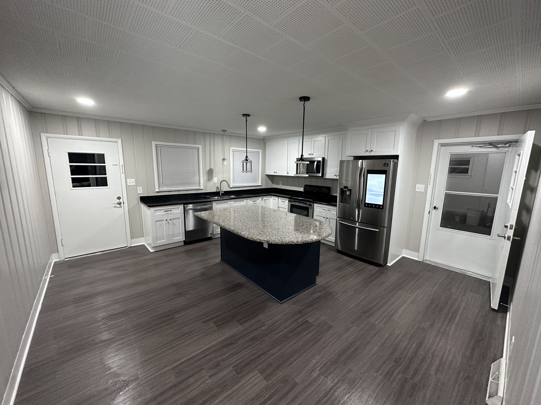 Finished kitchen remodel with white cabinets, island, and updated flooring